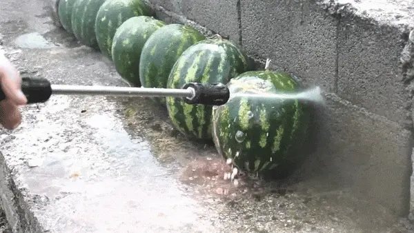 A pressure jet slicing through a row of melons lined up on a wall